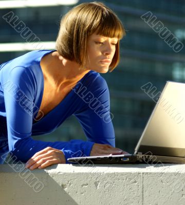 Young woman with a laptop in a blue dress.
