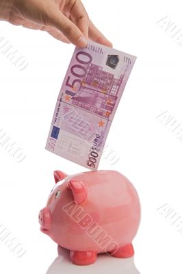 Saving a note of five hundred euros in a piggy-bank