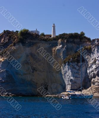 Lighthouse on steep mountain and sail yacht