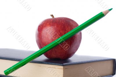 A red apple with green pencil on top of many books A red apple with green pencil on top of many books