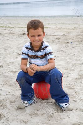 Beautiful boy sitting on a ball on the beach
Beautiful boy sitti