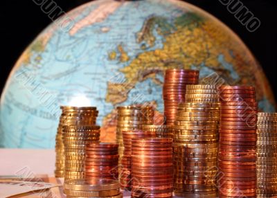Stacks of Euro and Cent coins in front of a globe