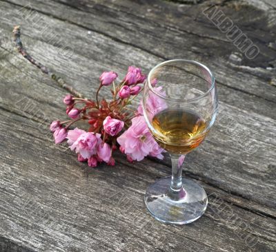Glass of cognac and flowers on a wooden ancient table
