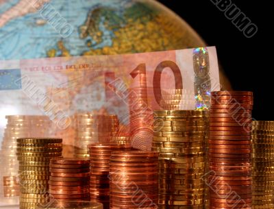 Stacks of Euro and Cent coins in front of a globe