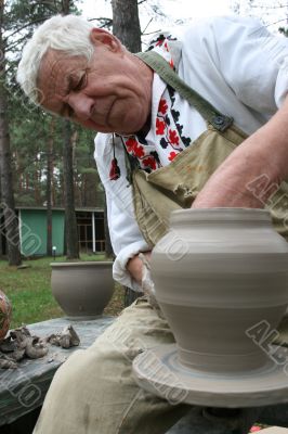 Old potter working with clay on wheel