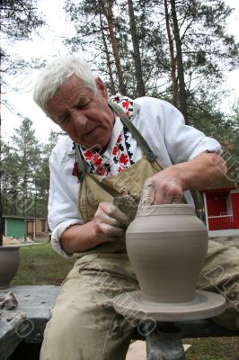 Old potter working with clay on wheel