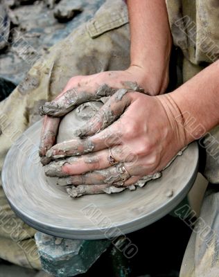 Hands shaping clay on potter`s wheel