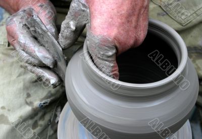 Hands shaping clay on potter`s wheel