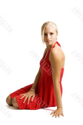 beuatiful blonde teenage girl sitting on floor in red dress