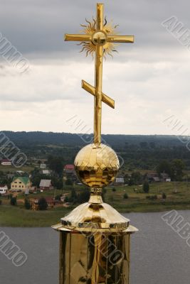 Gold cross with belltower`s reflection