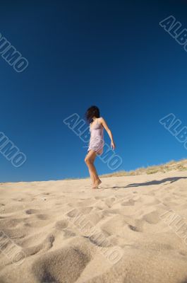 dressed woman walking on the sand