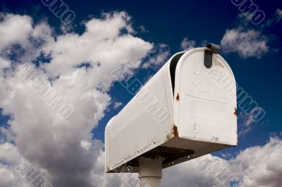 Weathered Old Mailbox Against Blue Sky and Clouds