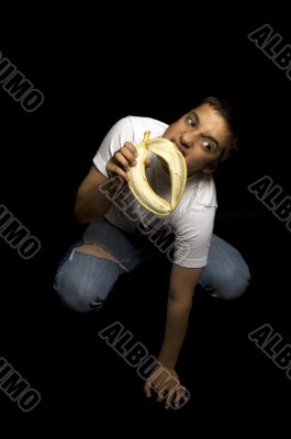 teenage boy is eating banana like a monkey