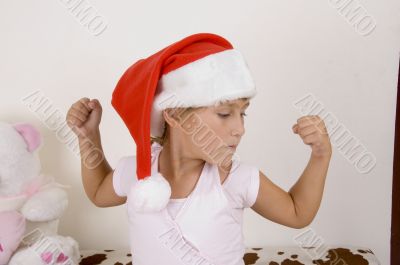 little girl wearing christmas hat and her muscles