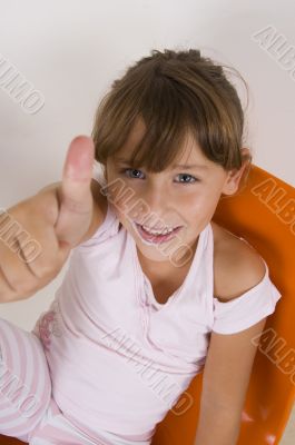smiling little girl showing thumb`s up hand