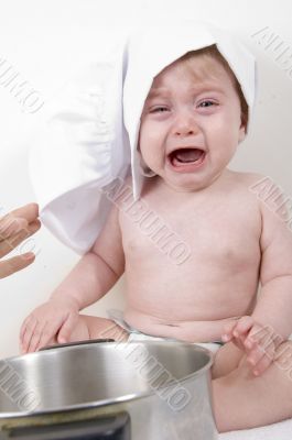 crying baby wearing chef hat and with pan