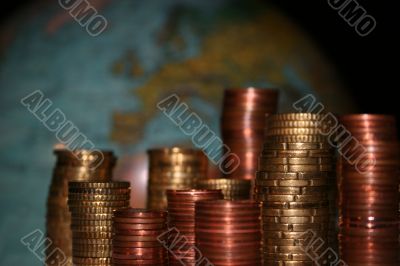 Stacks of Euro and Cent coins in front of a globe