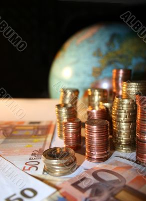Stacks of Euro and Cent coins in front of a globe