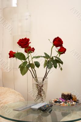 Vase with flowers and remote-controls on a table