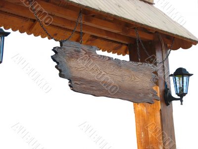 Old wooden board hanging from chains under roof