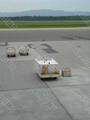 empty airplane gate with small trucks