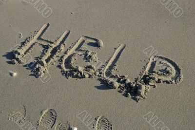 Help inscription on a sand beach