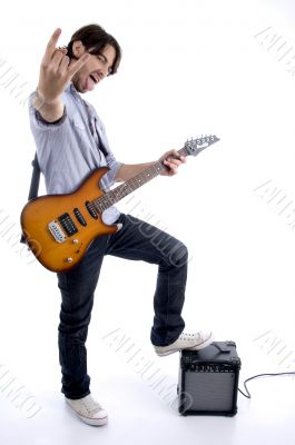 young rock star holding guitar with leg on speaker