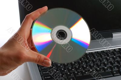 Close up. Woman with cd disk in a hand used notebook
