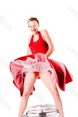 Funny girl in red gala dress playing with a ventilator laughing