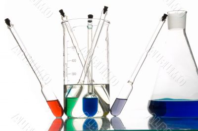red, blue and green retorts with liquids, white background, close-up