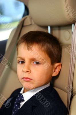 Little serious student go to school in car