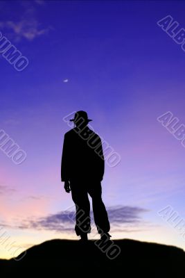 Silhouette of lone man on mountain in twilight