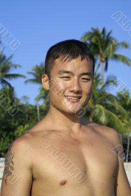 Fit asian man smiling on beach