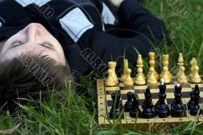 Woman lying in the grass near the chess board