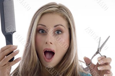 surprised woman holding scissor and comb