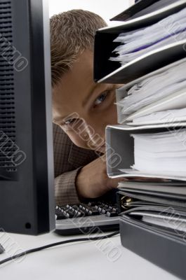 young man looking between the files and computer