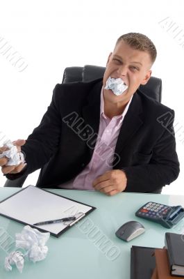 frustrated businessman with paper in his mouth