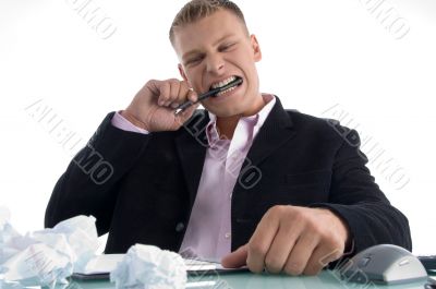 frustrated man biting on pen with teeth