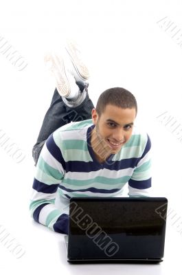 young male lying on the floor and busy with laptop