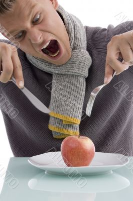 young man going to eat apple with fork and knife