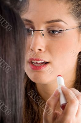 beautician applying lipstick on female lips