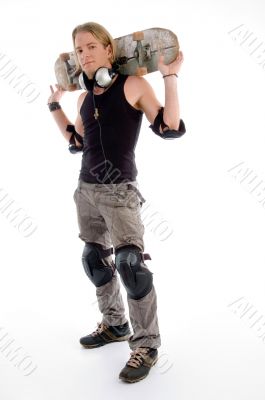 young male holding skateboard on his neck back young male holding skateboard on his neck back