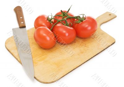 Red tomatoes and kitchen knife on a chopping board
