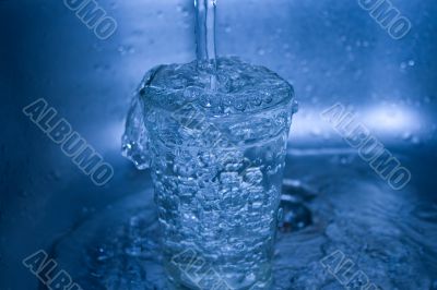 Water flowing in glass in dark blue tones