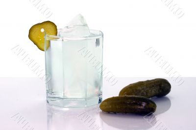 Vodka with ice in glass and salt cucumbers