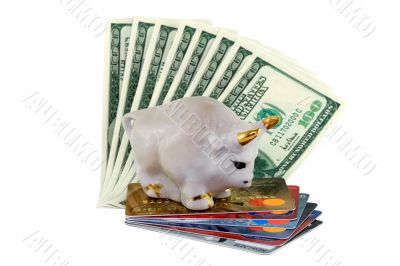 Figure of a white bull with gold horns standing on a pile of credit cards and dollars