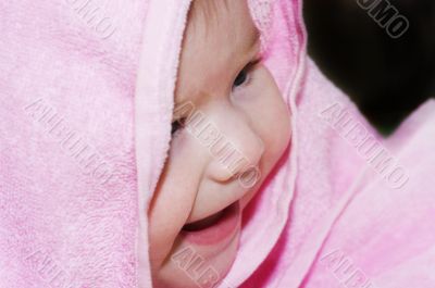 baby looking out and smiling from under blanket