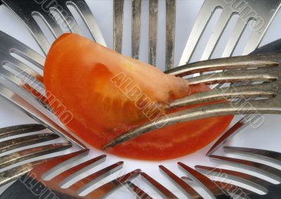 Struggle of forks for a tomato slice.