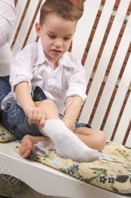 Adorable Young Boy Getting Socks On