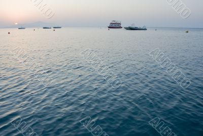 Sunrise with pink sky and  few boats